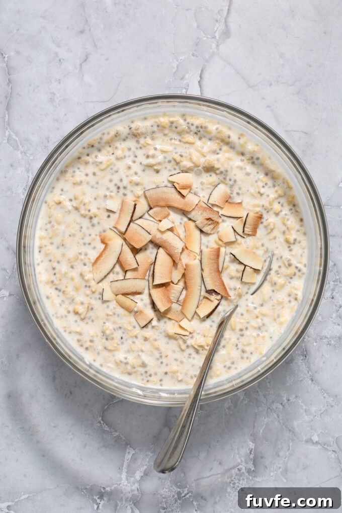 Coconut cream pie overnight oats in a mixing bowl with coconut flakes.