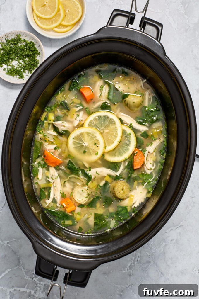 Lemon chicken artichoke soup in the slow cooker with lemon slices.