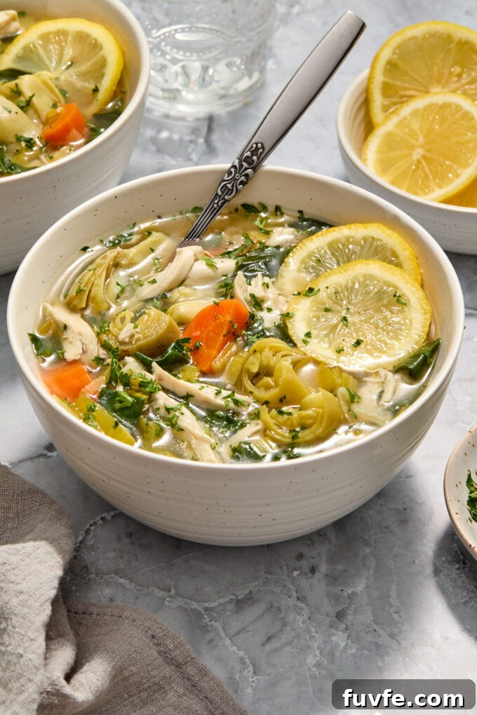 Lemon chicken soup with artichokes in a bowl.