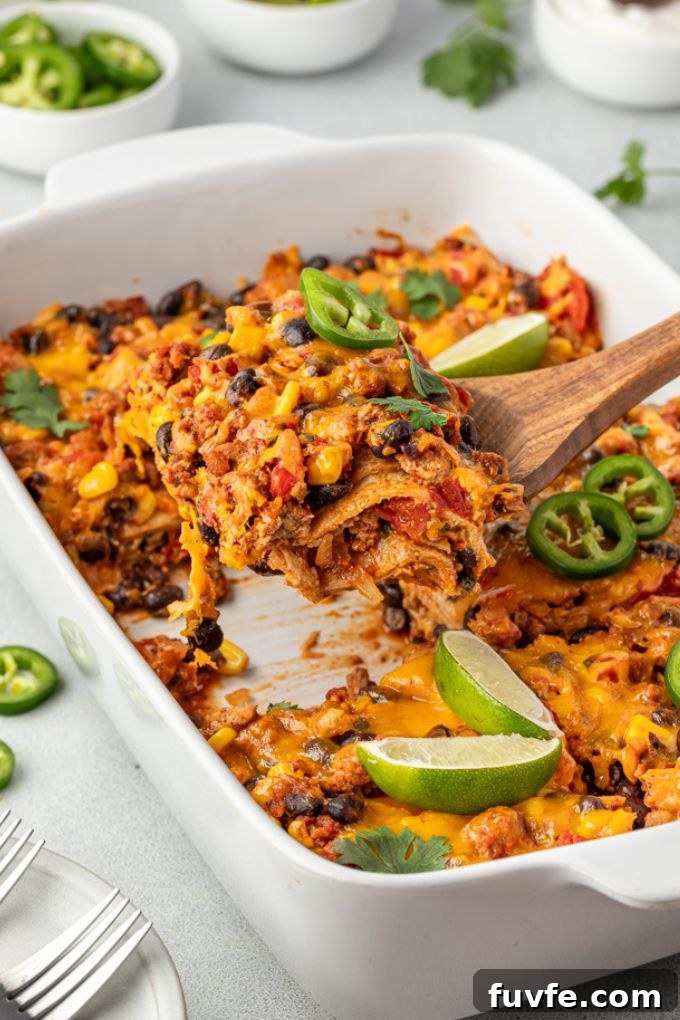 Cheesy Mexican Tortilla Casserole with Beans 7 Serving of Mexican tortilla casserole being lifted out of baking dish