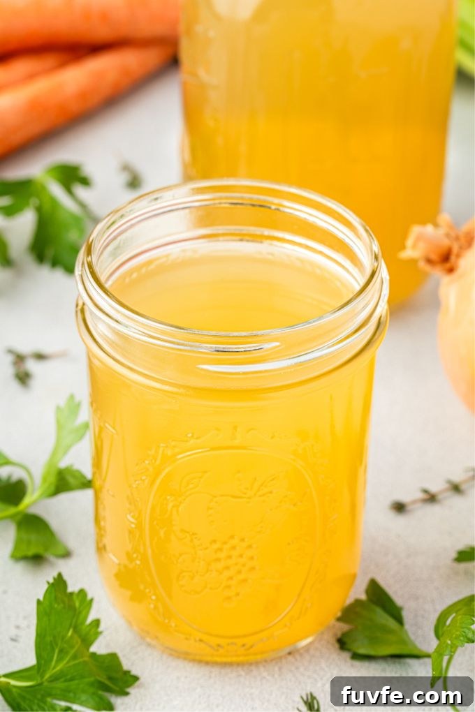 Flavorful Homemade Chicken Stock Recipe for Soups and Sauces 8 Homemade chicken stock in a jar with ingredients surrounding it