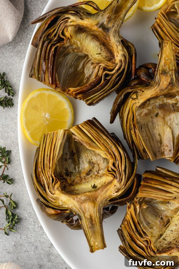 Baked artichokes on a platter with lemon and thyme