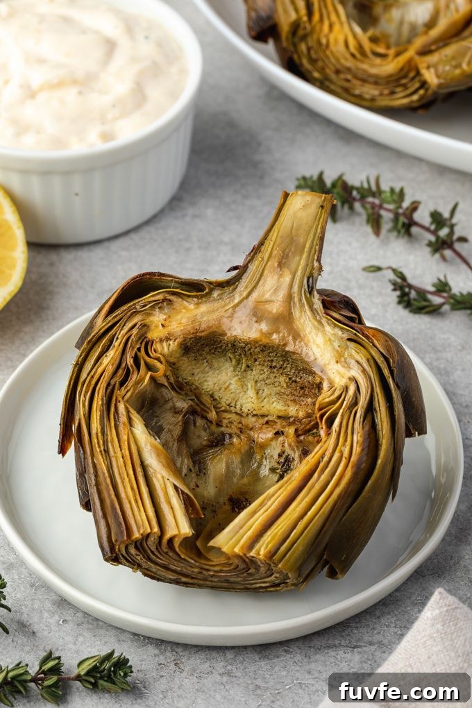 Roasted artichoke on a plate with aioli and thyme