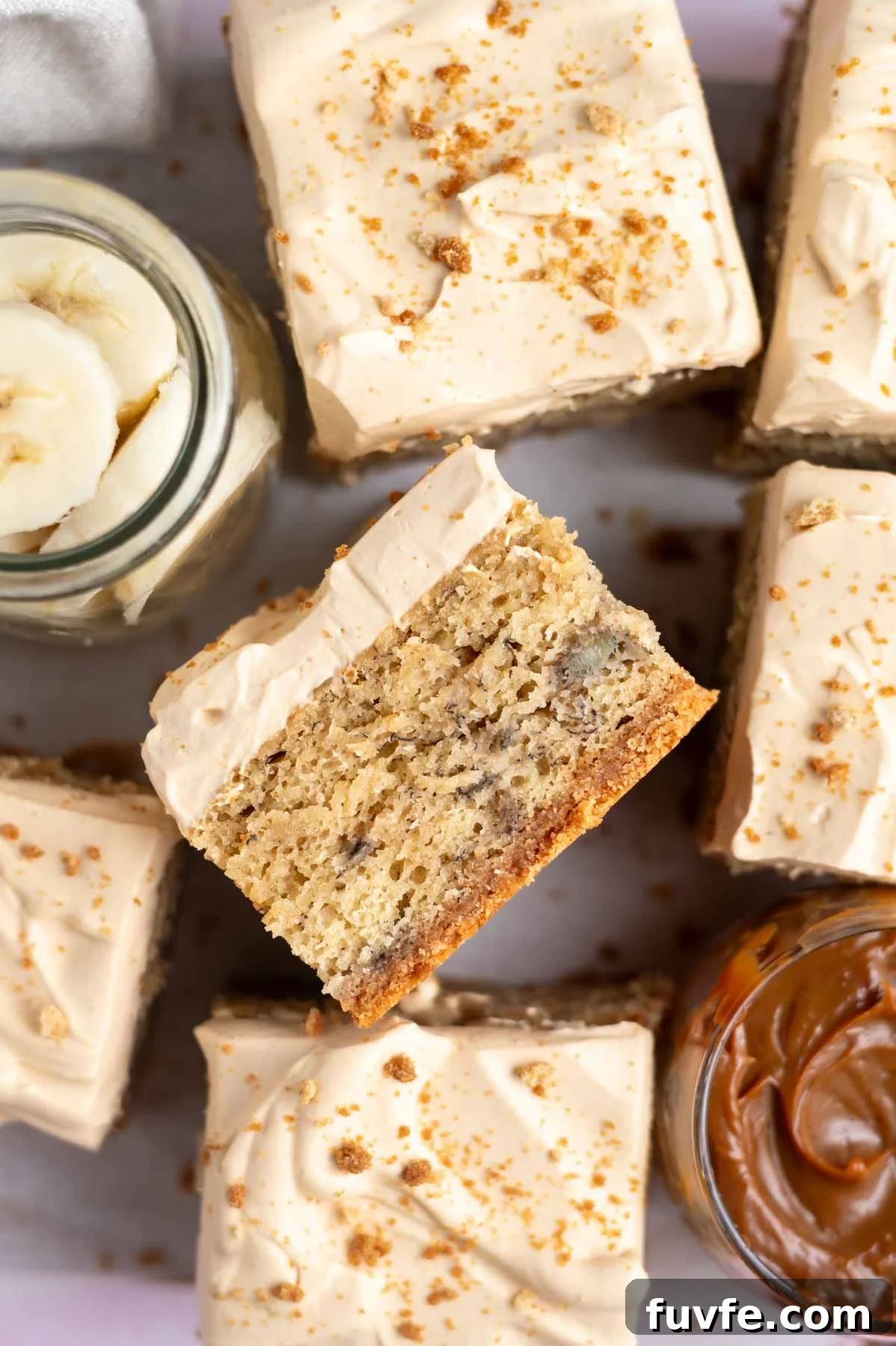 Decadent Banoffee Cake Recipe with Caramelized Banana Layers 3 slice of cake on it's side showing graham cracker crust, banana cake and whipped cream frosting