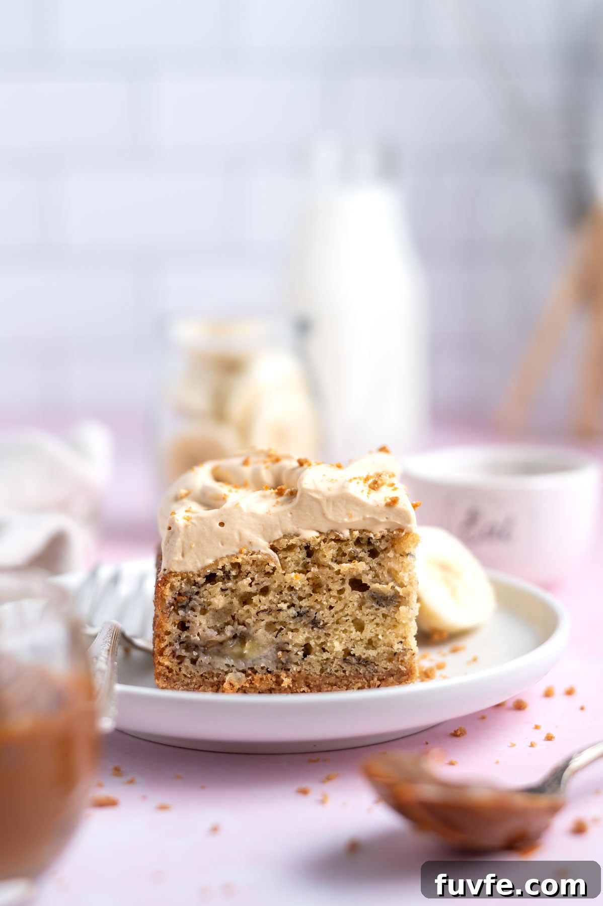 Decadent Banoffee Cake Recipe with Caramelized Banana Layers 5 slice of cake on a plate with milk and banana slices in the background