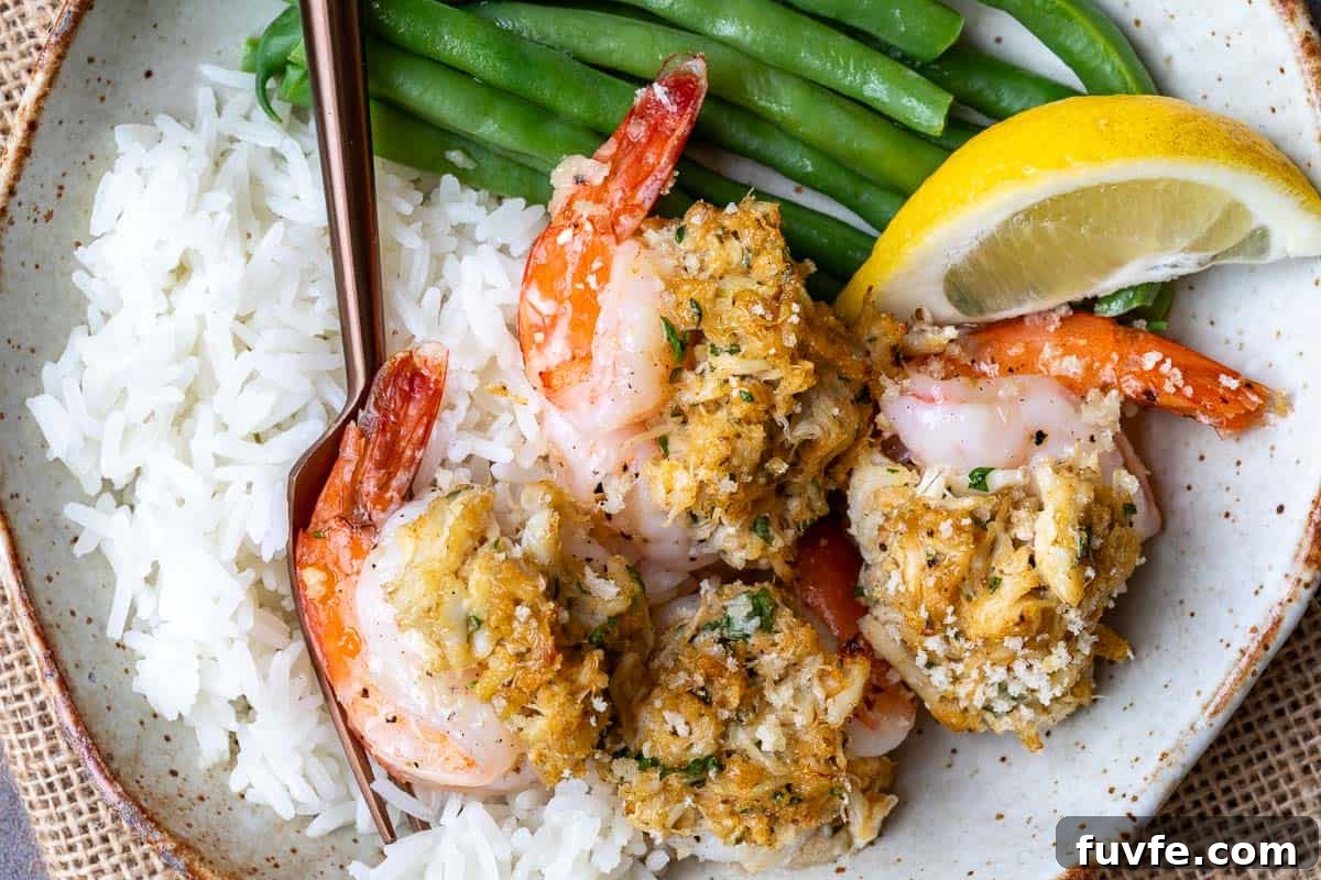 Oven-Baked Stuffed Shrimp with Garlic Herb Breadcrumbs 11 plate with baked crab stuffed shrimp along with rice, fork, green beans, and lemon wedge.