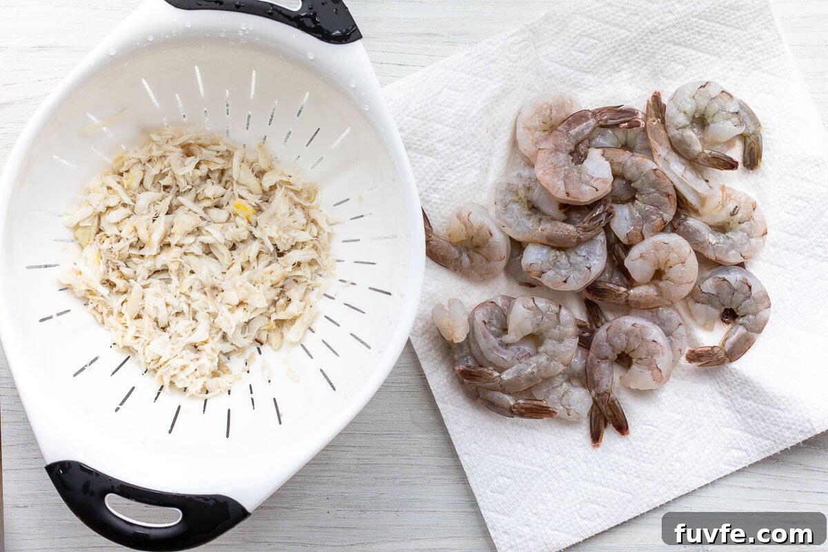 Oven-Baked Stuffed Shrimp with Garlic Herb Breadcrumbs 4 crabmeat in strainer next to pile of deveined shrimp on paper towel.