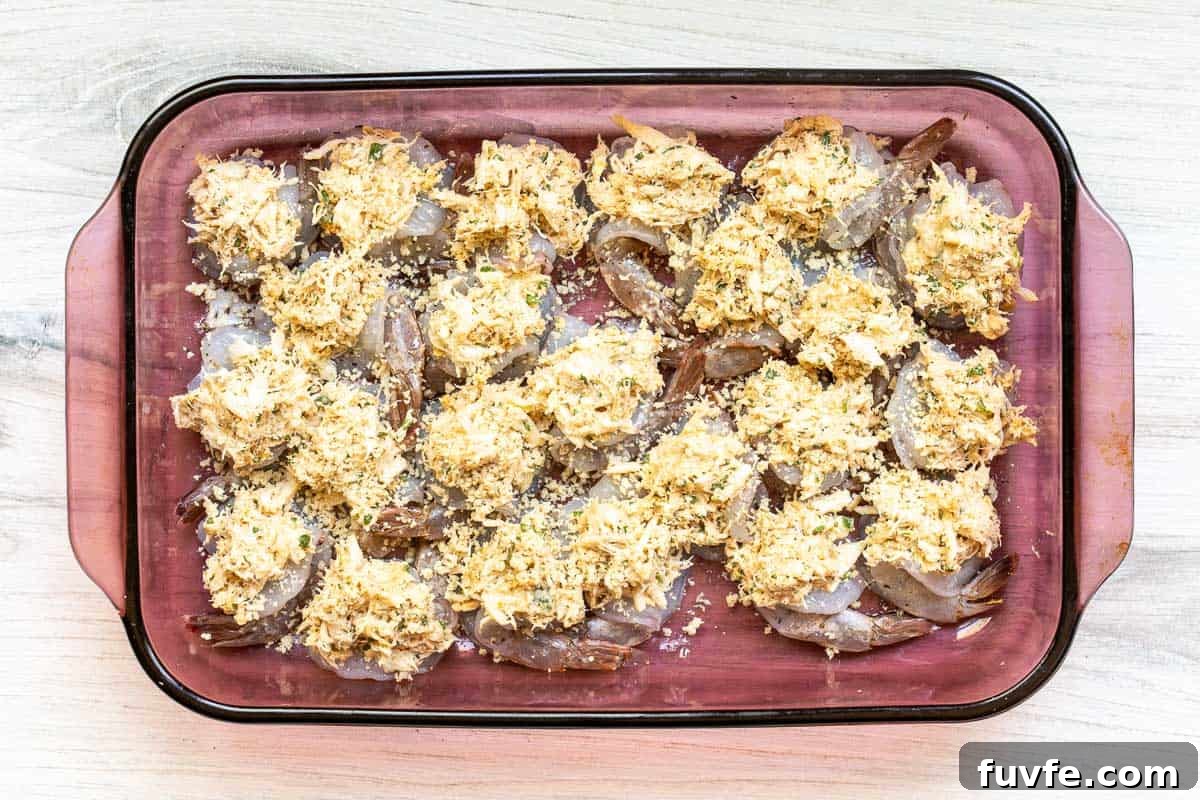 Oven-Baked Stuffed Shrimp with Garlic Herb Breadcrumbs 8 butterflied shrimp topped with crab mixture in baking dish before baking.