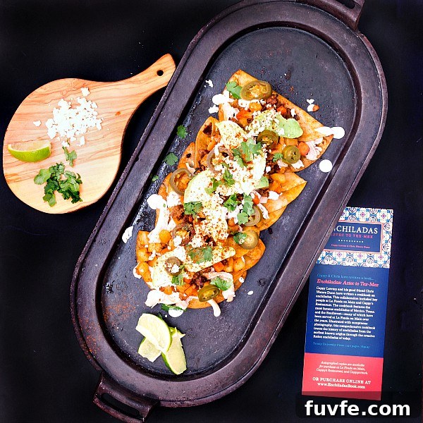 Chicken and Chorizo Enchiladas: From Aztec Roots to Tex‑Mex Favorites 4 Overhead shot of a platter of enchiladas, a cutting board with cotija cheese, a lime segment, and cilantro.