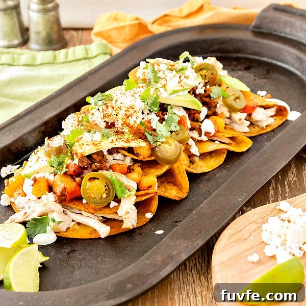 Chicken and Chorizo Enchiladas: From Aztec Roots to Tex‑Mex Favorites 5 A platter of Mexican food topped with pickled jalapenos, lime, crema, cilantro, and cotija cheese.