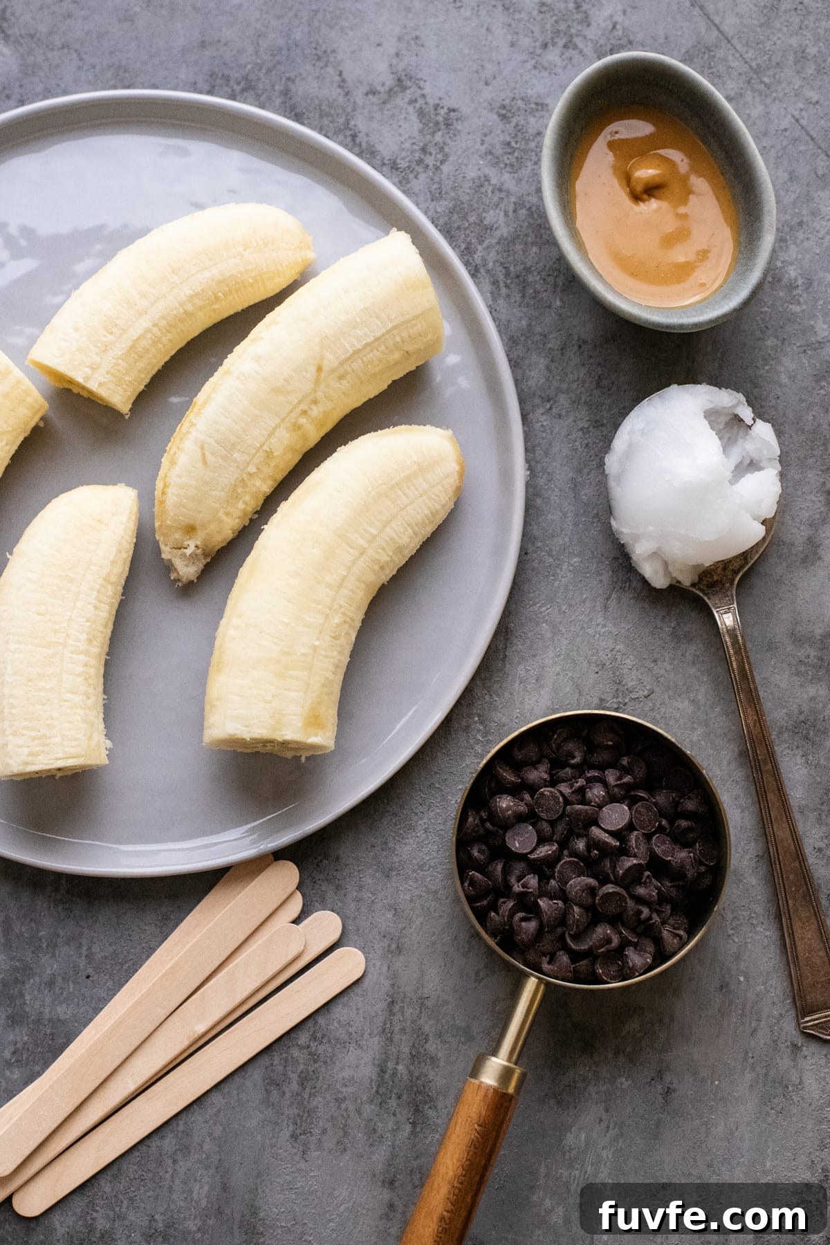 ingredients for frozen chocolate-covered bananas arranged on dark gray background.