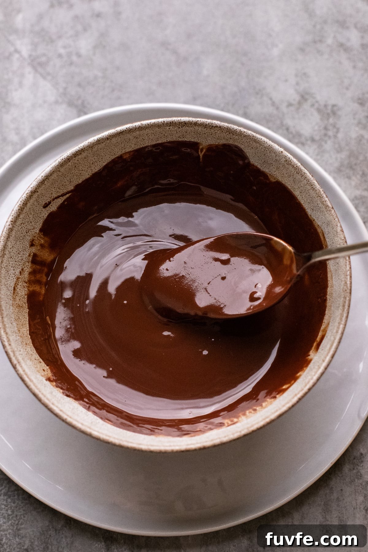 ceramic bowl with melted chocolate and a spoon in it.