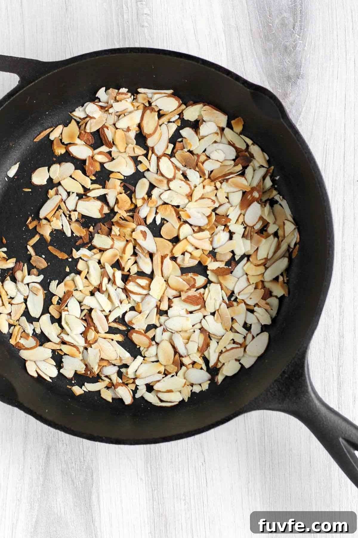 Toasted sliced almonds in a cast iron skillet.