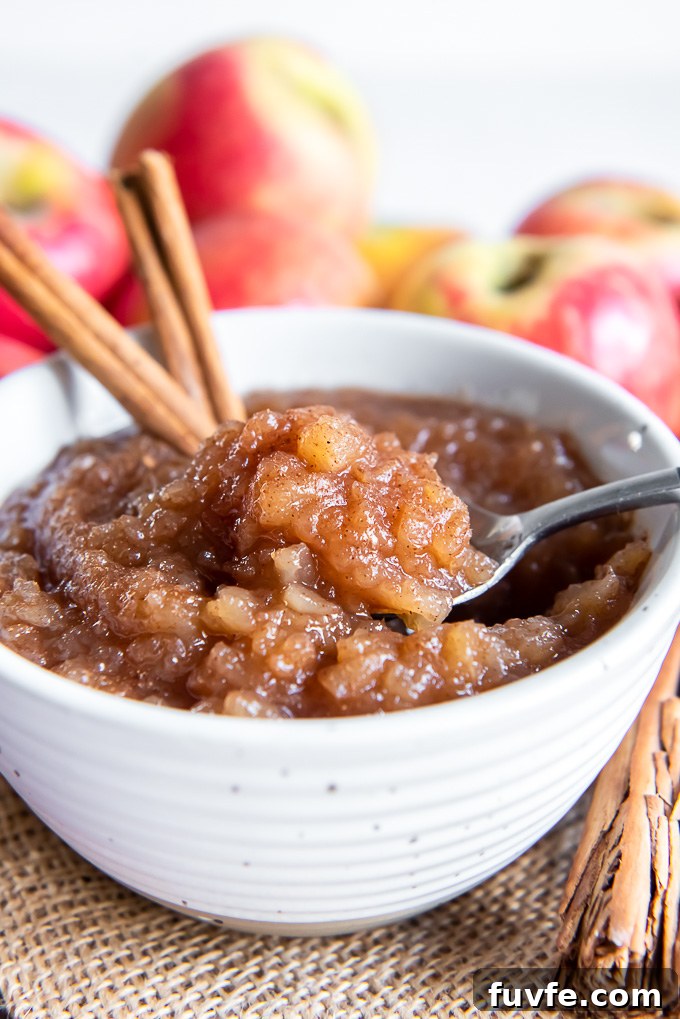 Homemade applesauce in a bowl with spoon digging into the center