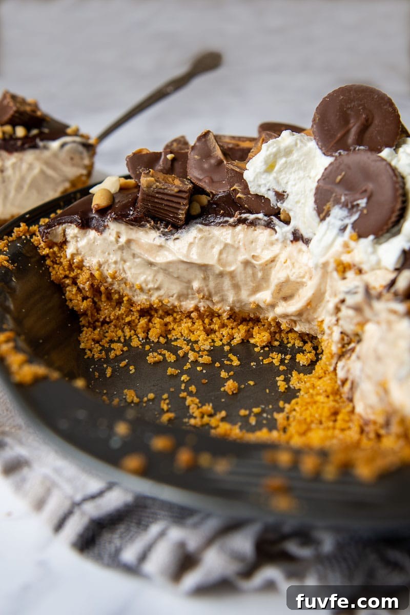 Decadent Chocolate Peanut Butter Pie Recipe for Parties 4 a slice taken out of a chocolate peanut pie with peanut butter cups on top