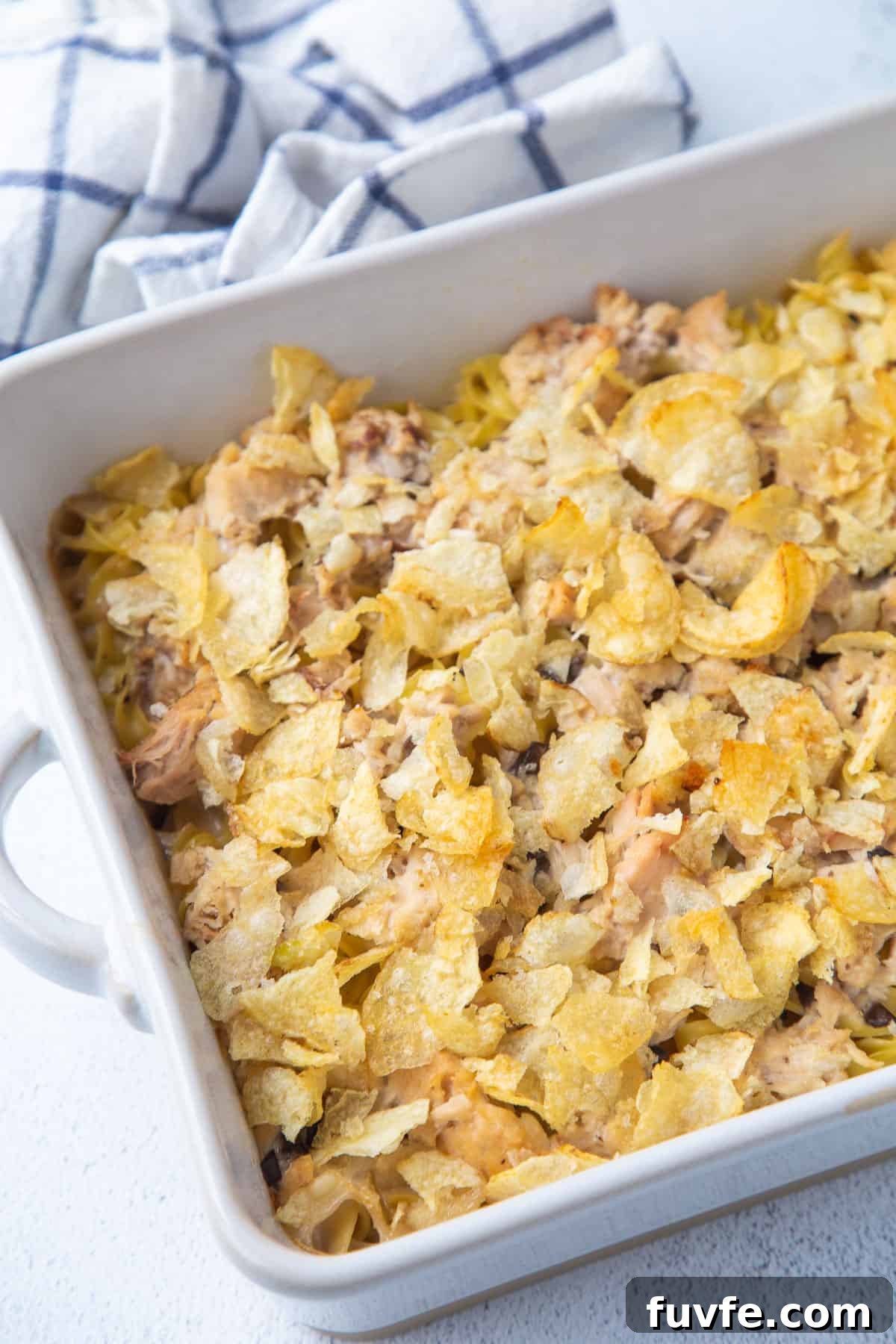 tuna noodle casserole topped with potato chips in a white casserole dish.