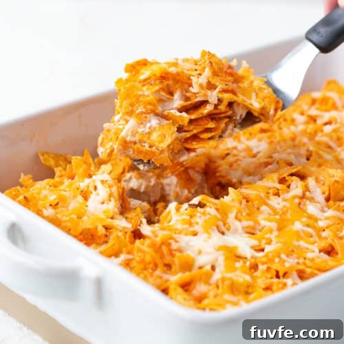 hand scooping up dorito chicken casserole with a spatula.
