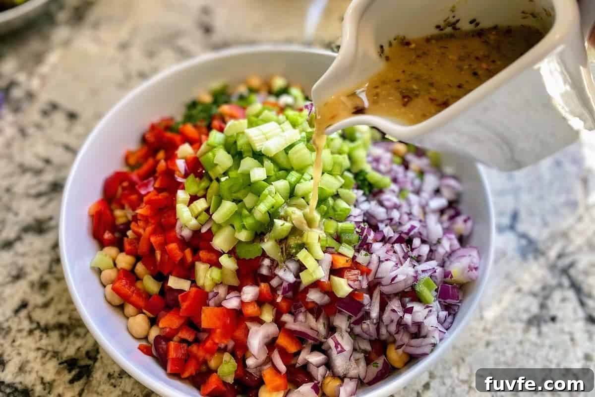 Oil-Free Bean Salad with Zesty Vinaigrette 7 I am pouring the salad dressing into a bowl of ingredients.