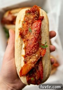 overhead shot of hand holding sausage peppers sandwich showing filling