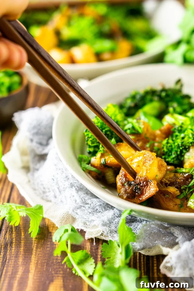 Chopsticks picking up a piece of shrimp in a vegetable bowl.