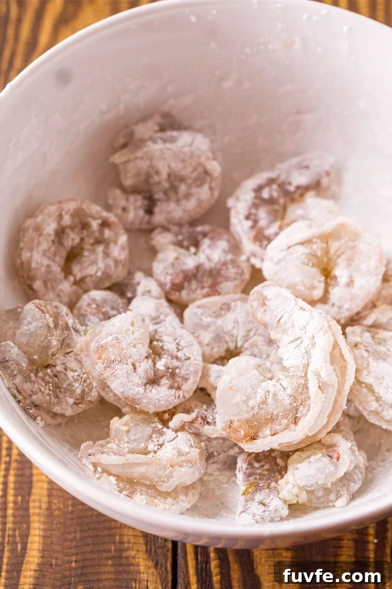 Shrimp coated in cornstarch in a white bowl.