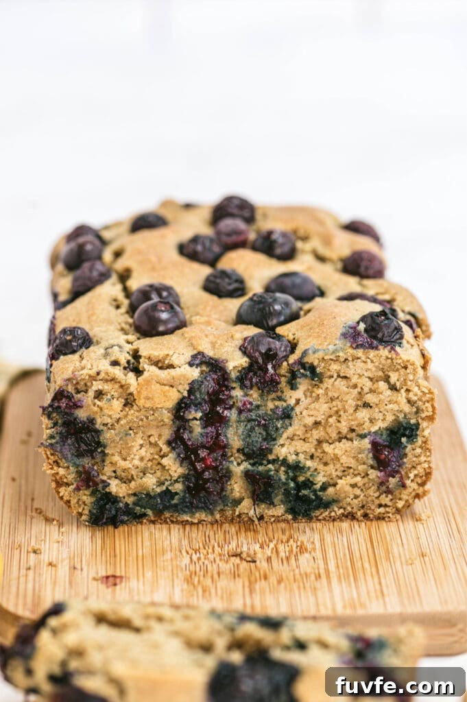 Lemon Blueberry Quick Bread Recipe for Moist Zesty Loaves 2 Closeup of lemon blueberry loaf on a cutting board with one slice removed from the bread