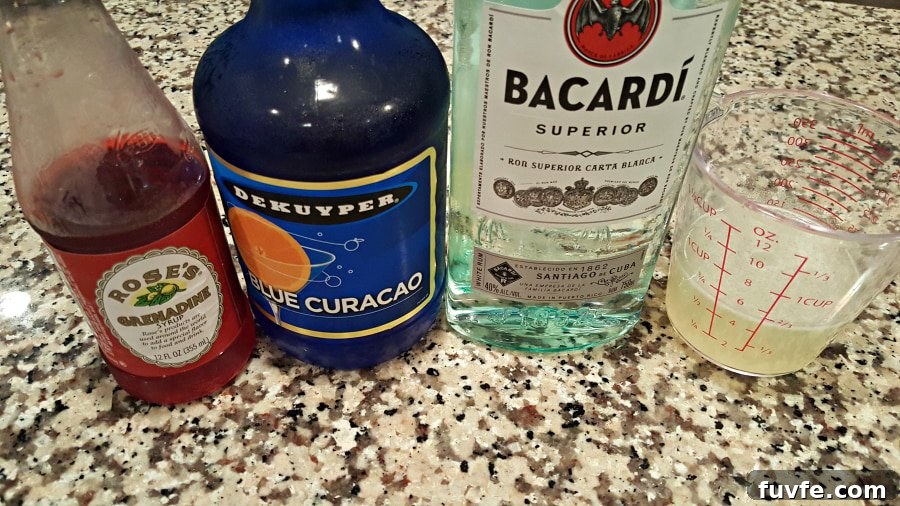 bottle of grenadine, bottle of blue curacao, bottle of bacardi, measuring cup with lemonade in it.