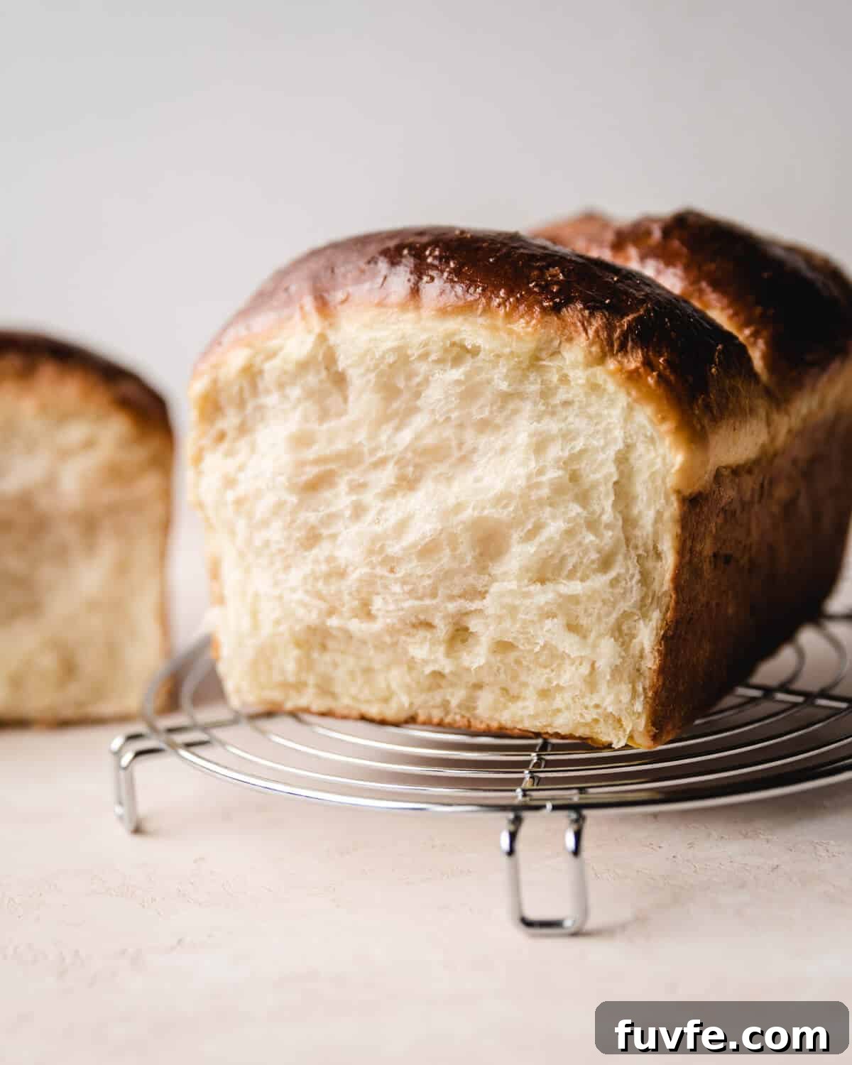 Creamy Condensed Milk Bread Recipe for Soft Homemade Loaf 2 Showing the side of a condensed milk bread loaf sitting on a cooling rack.