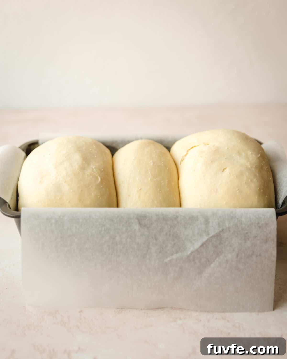 Creamy Condensed Milk Bread Recipe for Soft Homemade Loaf 34 3 pieces of risen dough in a loaf pan.