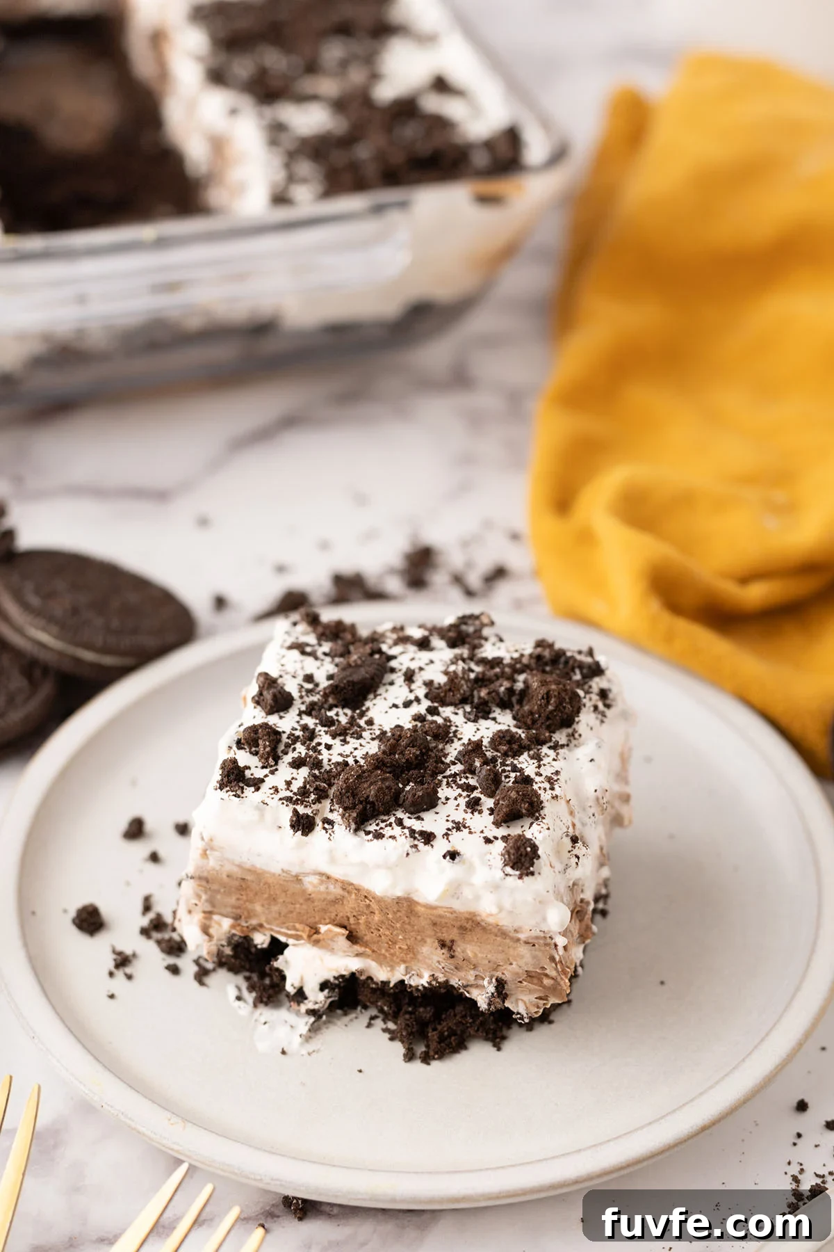 Slice of chocolate lasagna on a plate topped with crushed Oreos.