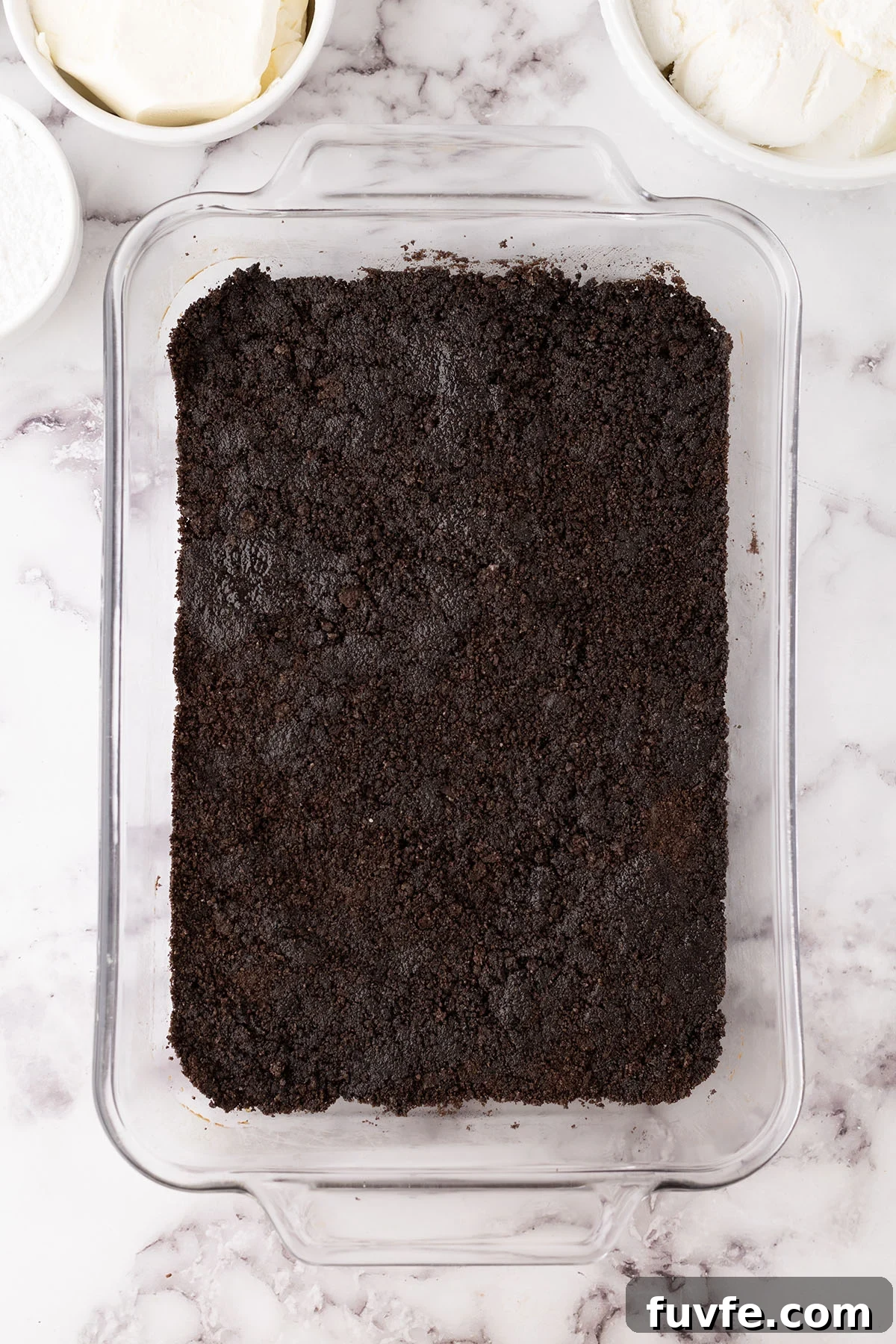 Crushed Oreos crust pressed into the bottom of a baking dish.