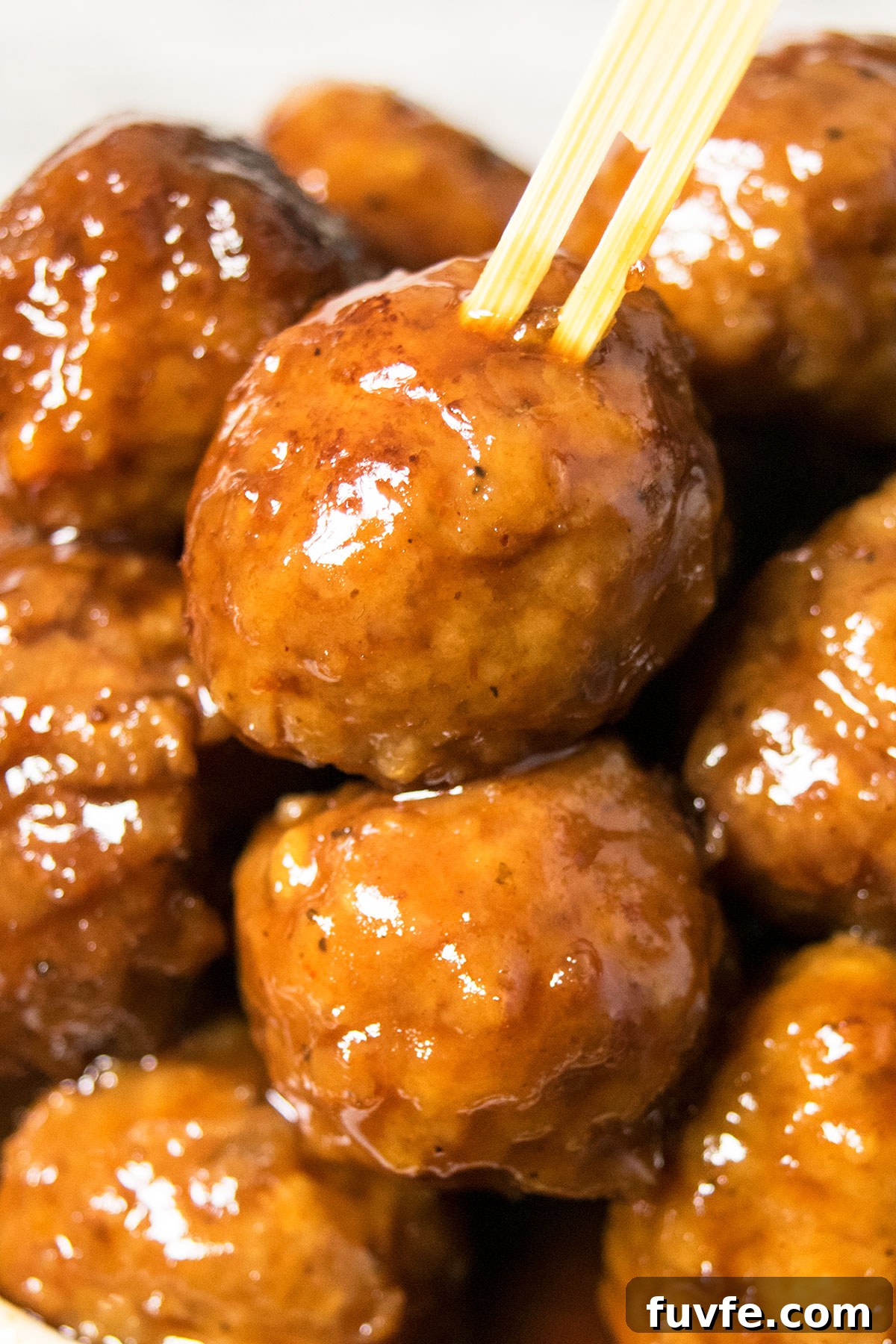Instant Pot Grape Jelly Meatballs Recipe—Sweet & Tangy Party Appetizer 2 Bamboo toothpick pushed into a sweet and sour meatball- Closeup shot.