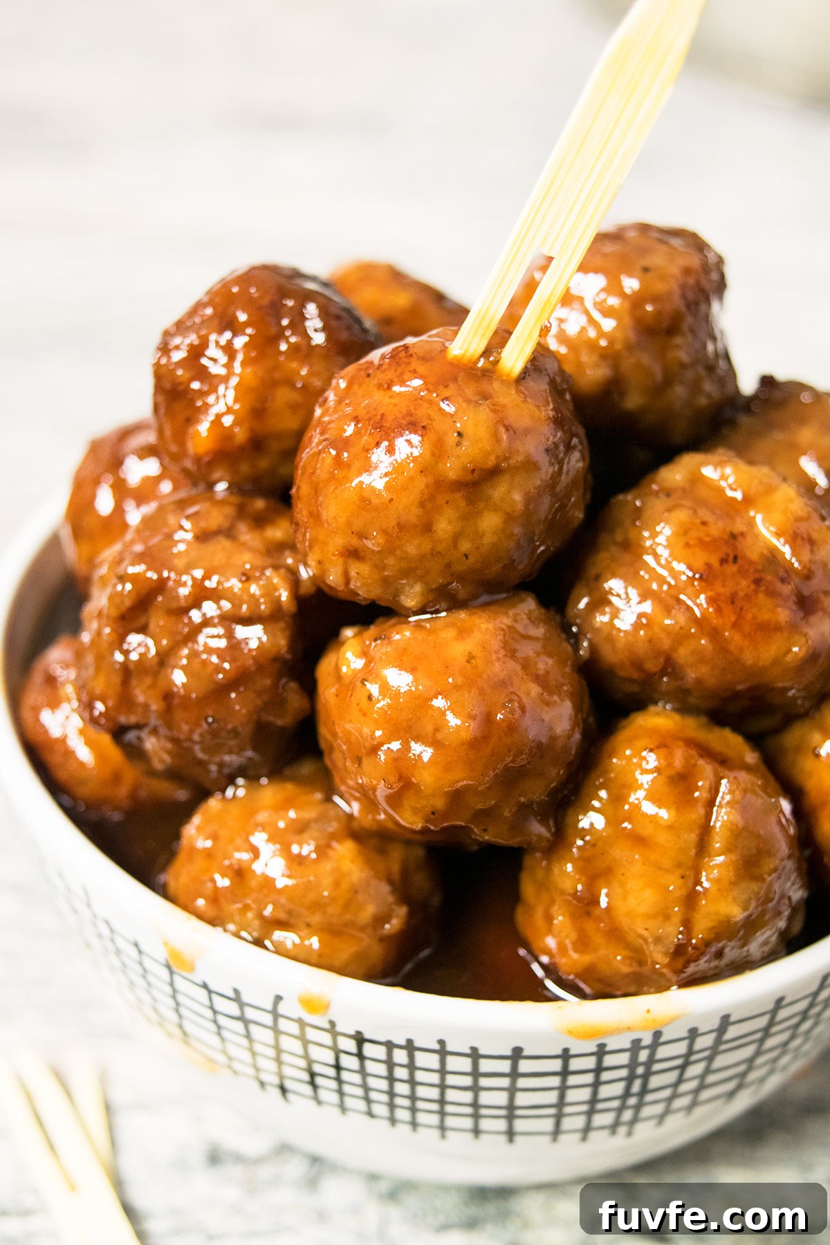 Instant Pot Grape Jelly Meatballs Recipe—Sweet & Tangy Party Appetizer 4 White bowl filled with cocktail meatballs with sauce dripping on the sides.