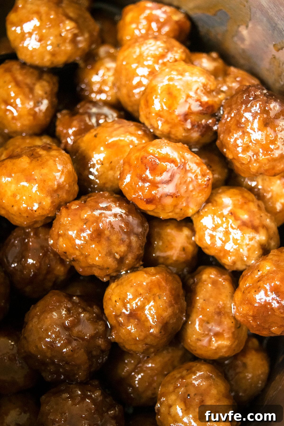 Instant Pot Grape Jelly Meatballs Recipe—Sweet & Tangy Party Appetizer 5 Appetizer meatballs coated in sauce in stainless steel pot- Overhead shot.