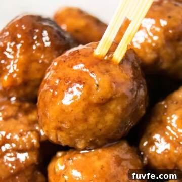 Instant Pot Grape Jelly Meatballs Recipe—Sweet & Tangy Party Appetizer 6 Bamboo toothpick being pushed into the best easy instant pot grape jelly meatballs.