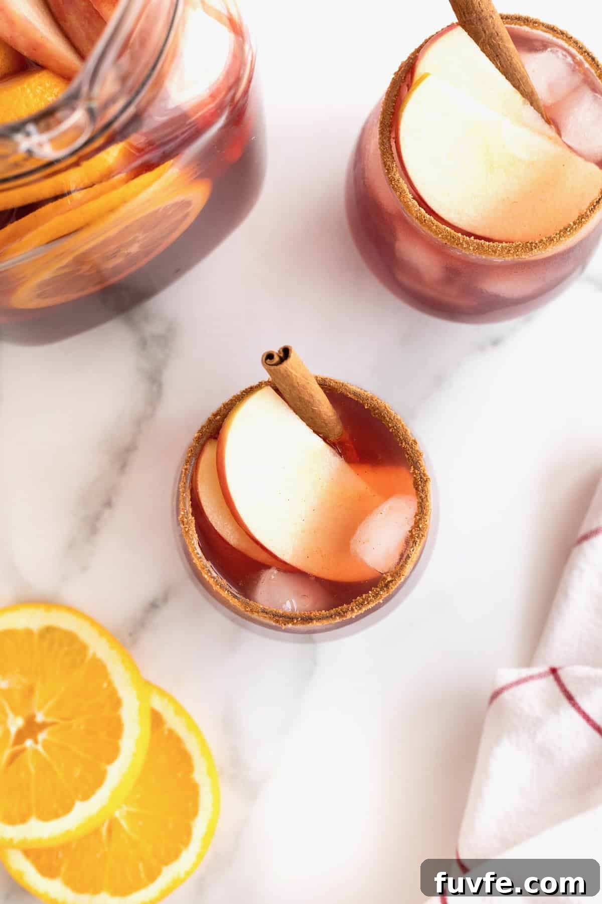 A glass of apple cider sangria garnished with apple slices and a cinnamon stick.