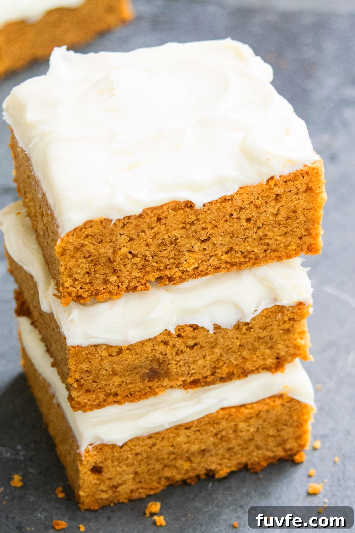 Stack of Easy Pumpkin Bars With Cream Cheese Frosting on Rustic Gray Background.
