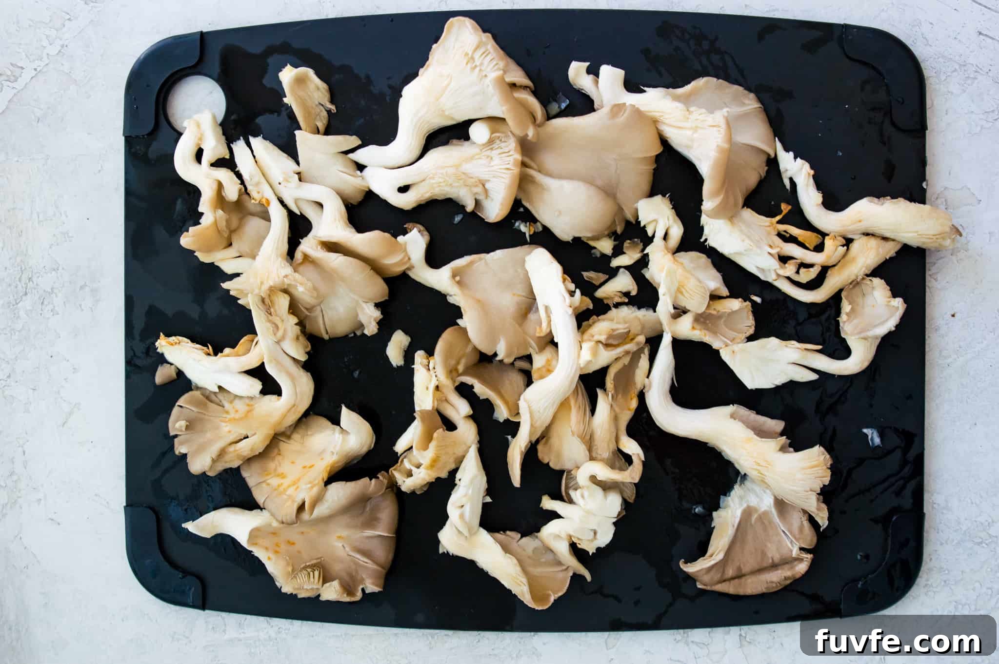 Crispy Pan-Fried Oyster Mushrooms with Garlic Butter 3 Cut oyster mushrooms on a cutting board.