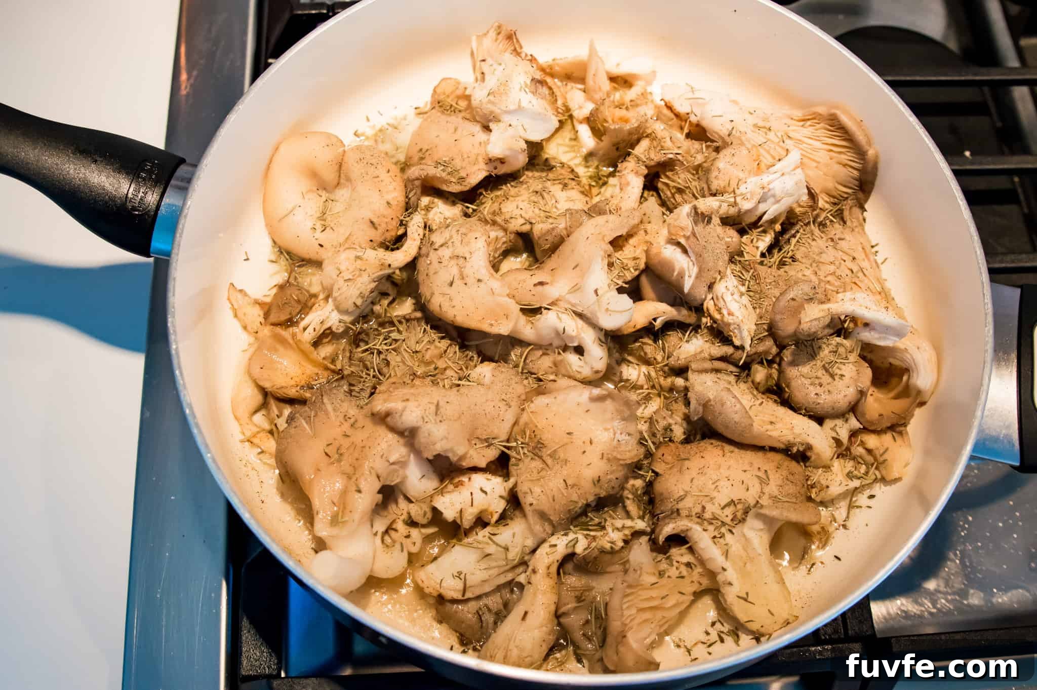 Crispy Pan-Fried Oyster Mushrooms with Garlic Butter 4 A pan on the stovetop filled with oyster mushrooms and spices.
