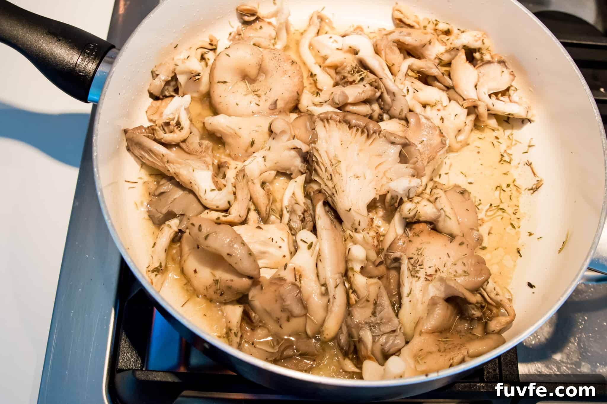 Crispy Pan-Fried Oyster Mushrooms with Garlic Butter 5 Oyster mushrooms cooking in a pan on the stovetop.