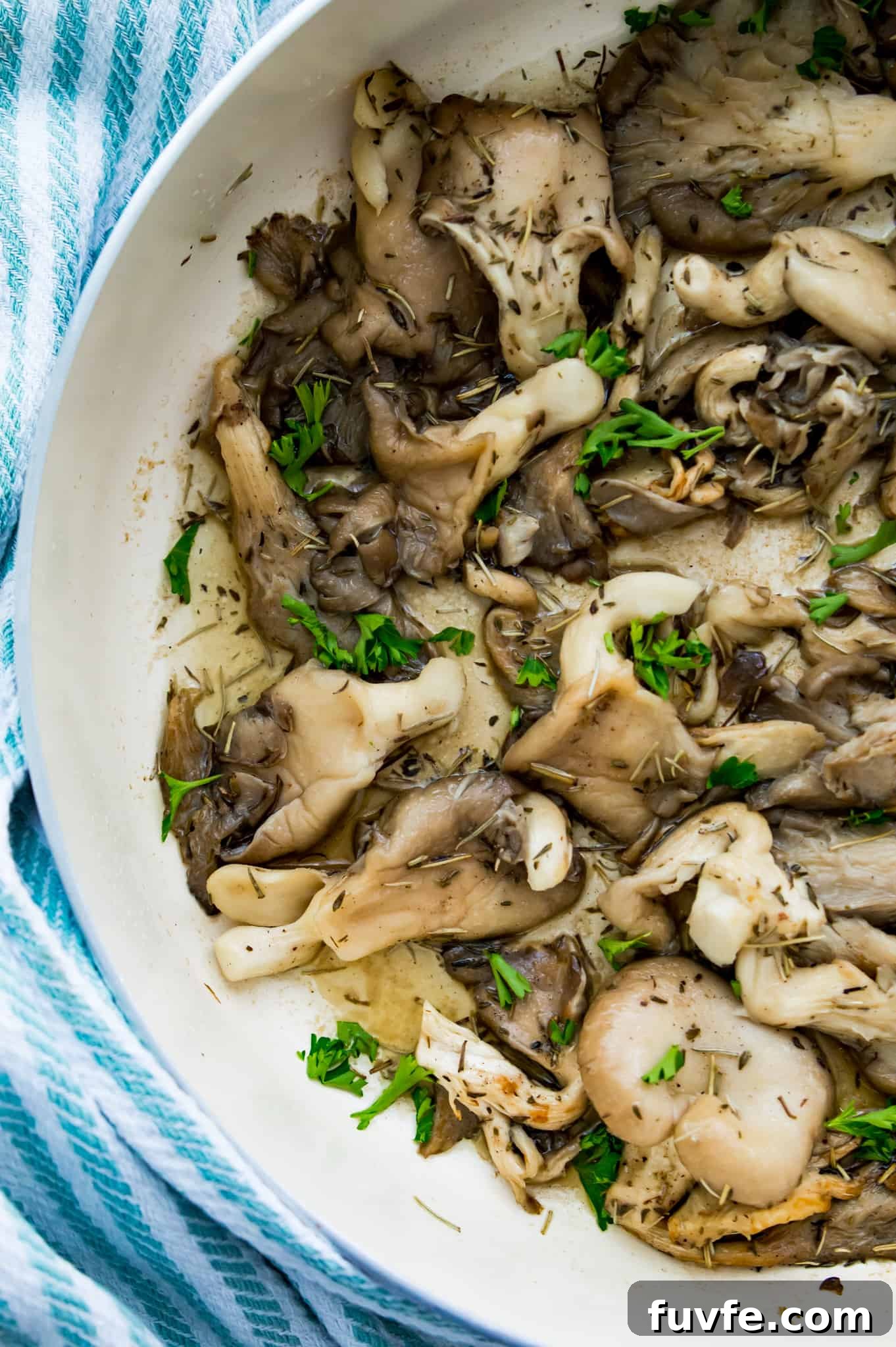 Crispy Pan-Fried Oyster Mushrooms with Garlic Butter 6 A pan of cooked oyster mushrooms with fresh herbs on top.