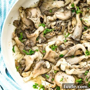 Crispy Pan-Fried Oyster Mushrooms with Garlic Butter 7 A pan of fried oyster mushrooms topped with fresh herbs.