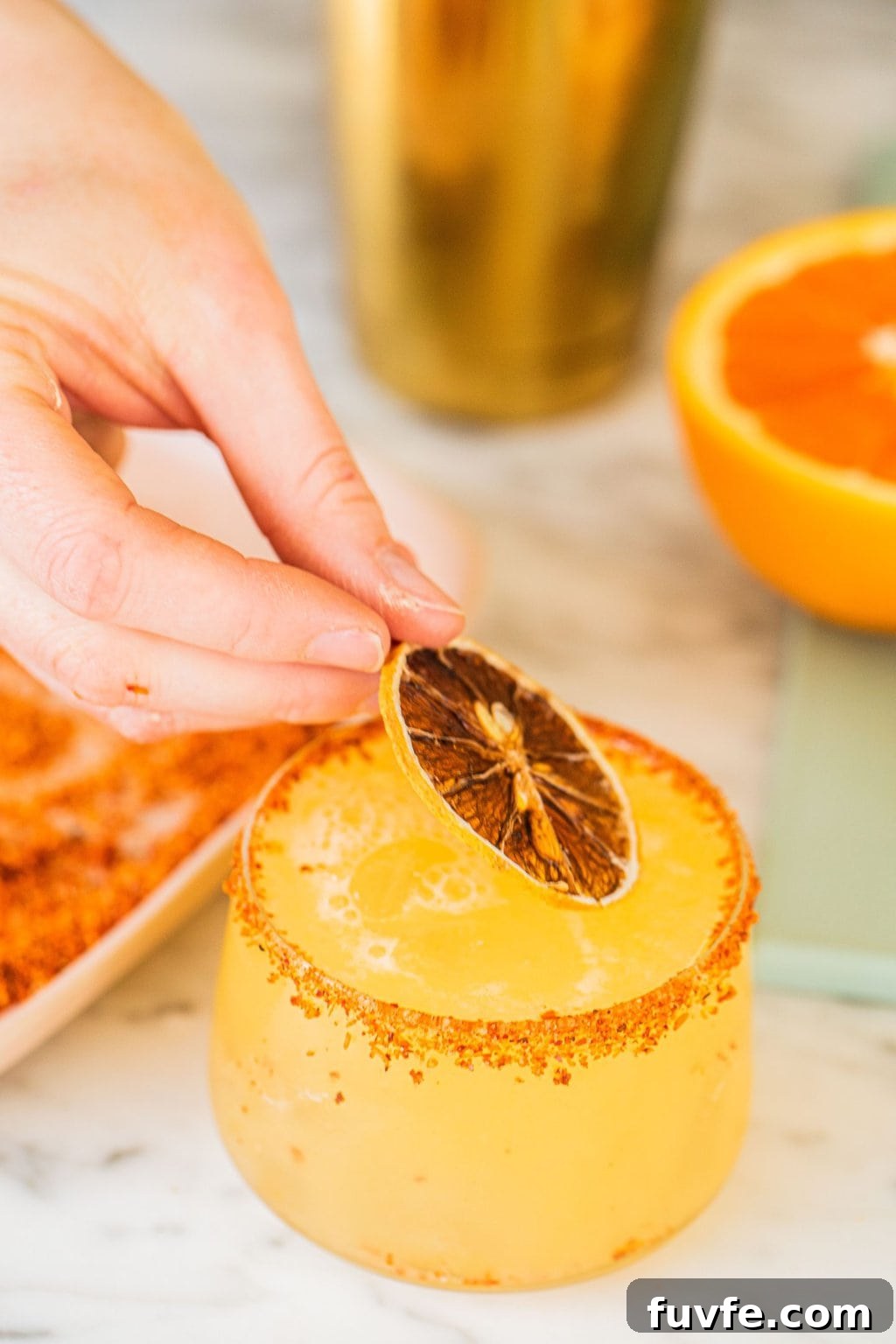 garnishing an orange margarita with a slice of the fruit