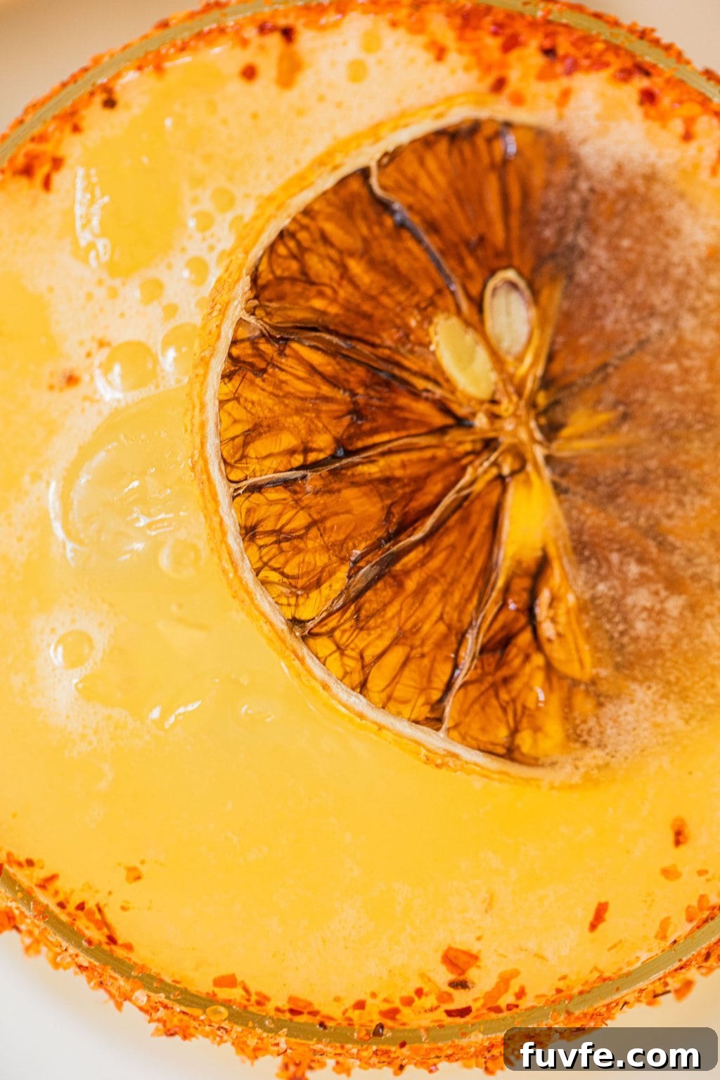 orange margarita with a slice of orange in it and tajin on the rim