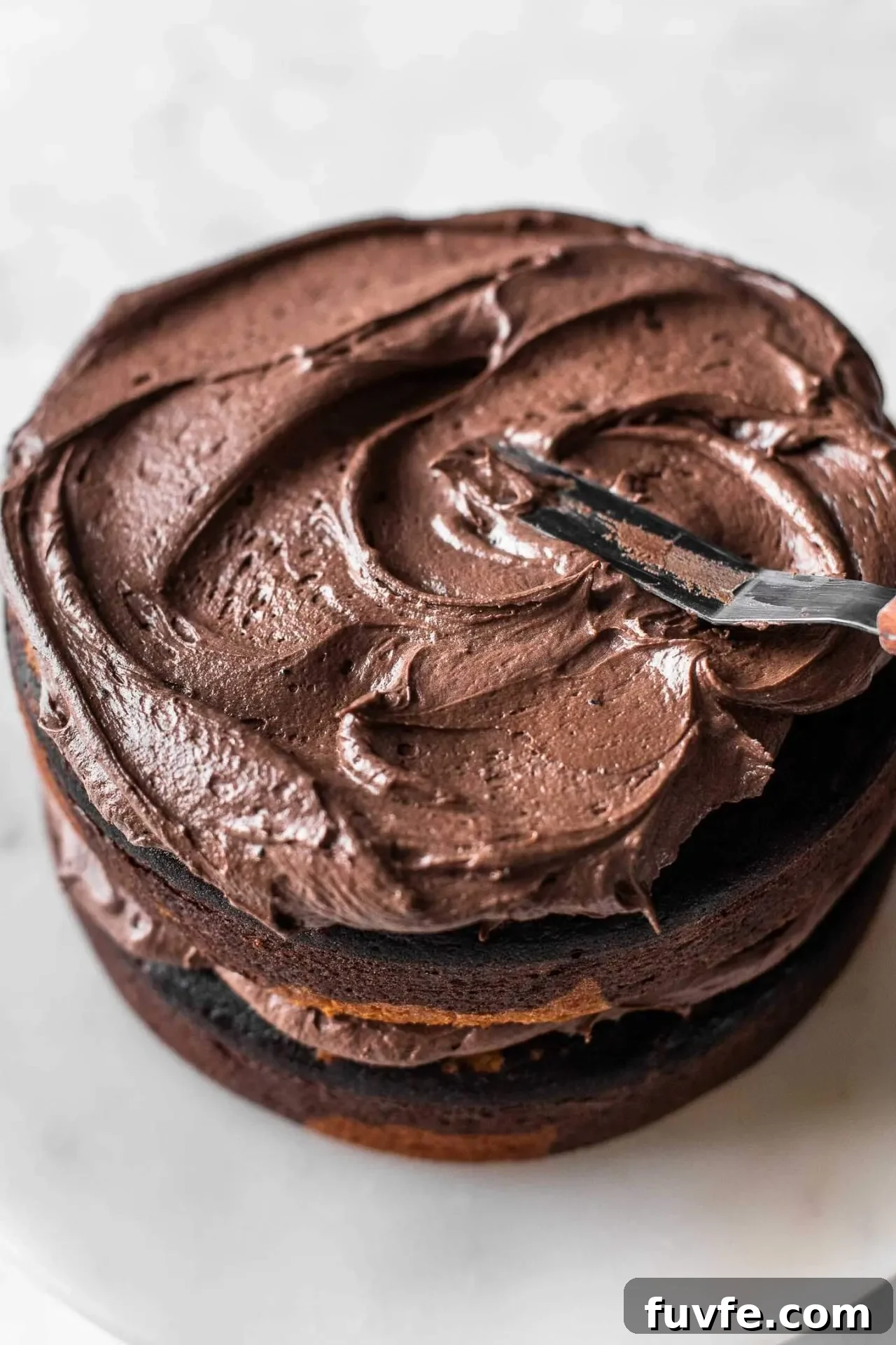 Classic Marble Cake Recipe with Swirled Chocolate-Vanilla Layers 12 marble cake chocolate frosting being spread on top of layered cakes