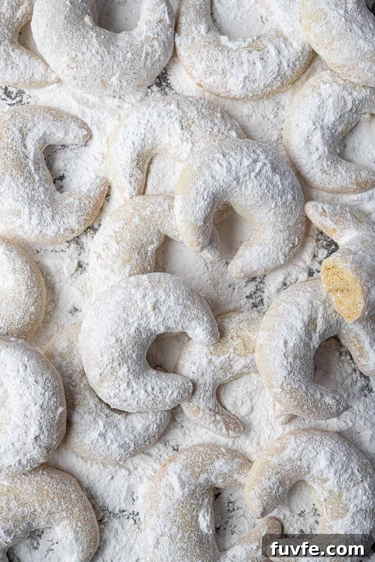 Vegan vanillekipferl on an icing sugar dusted surface.