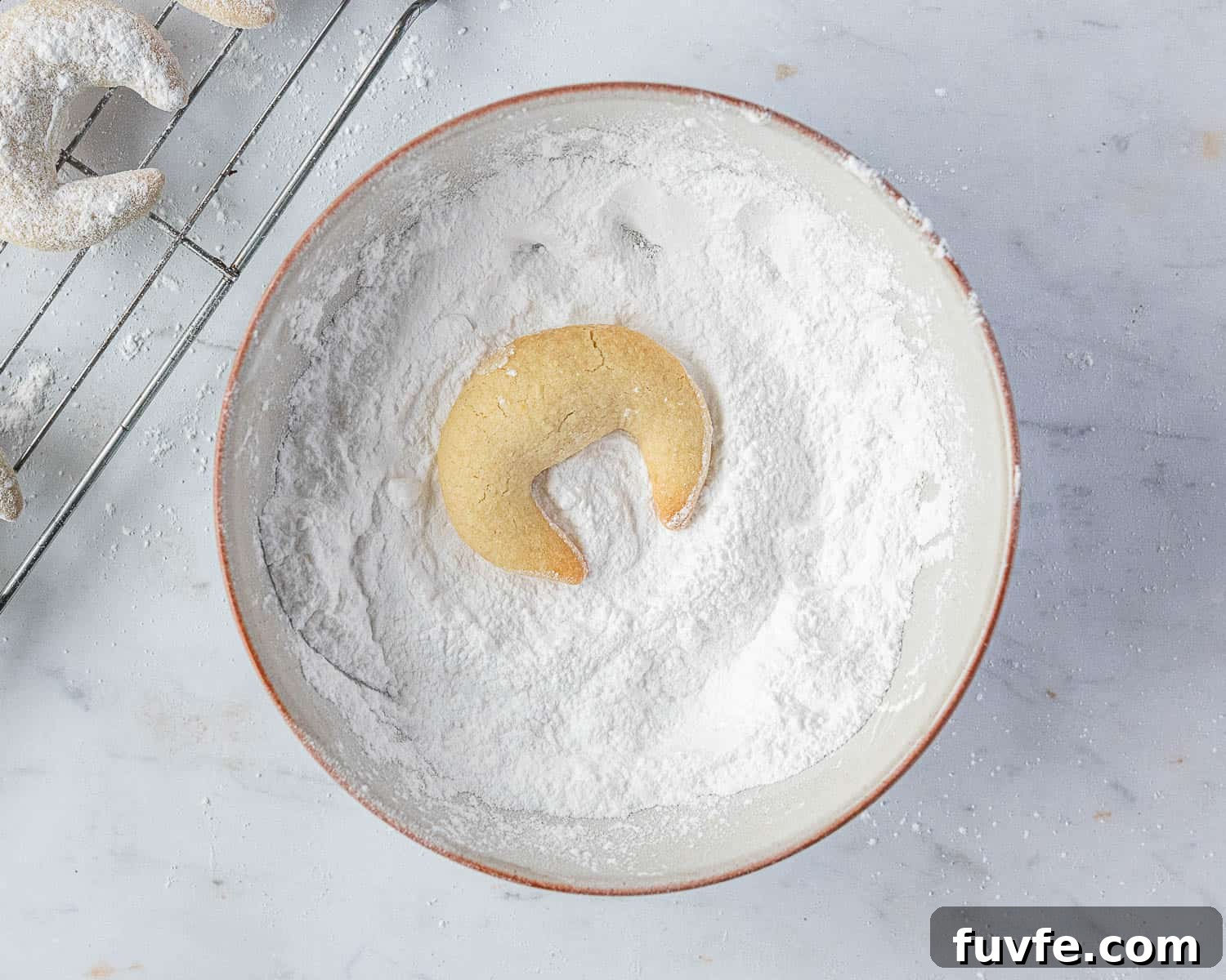 Step 6, rolling the vanillekipferl in icing sugar.
