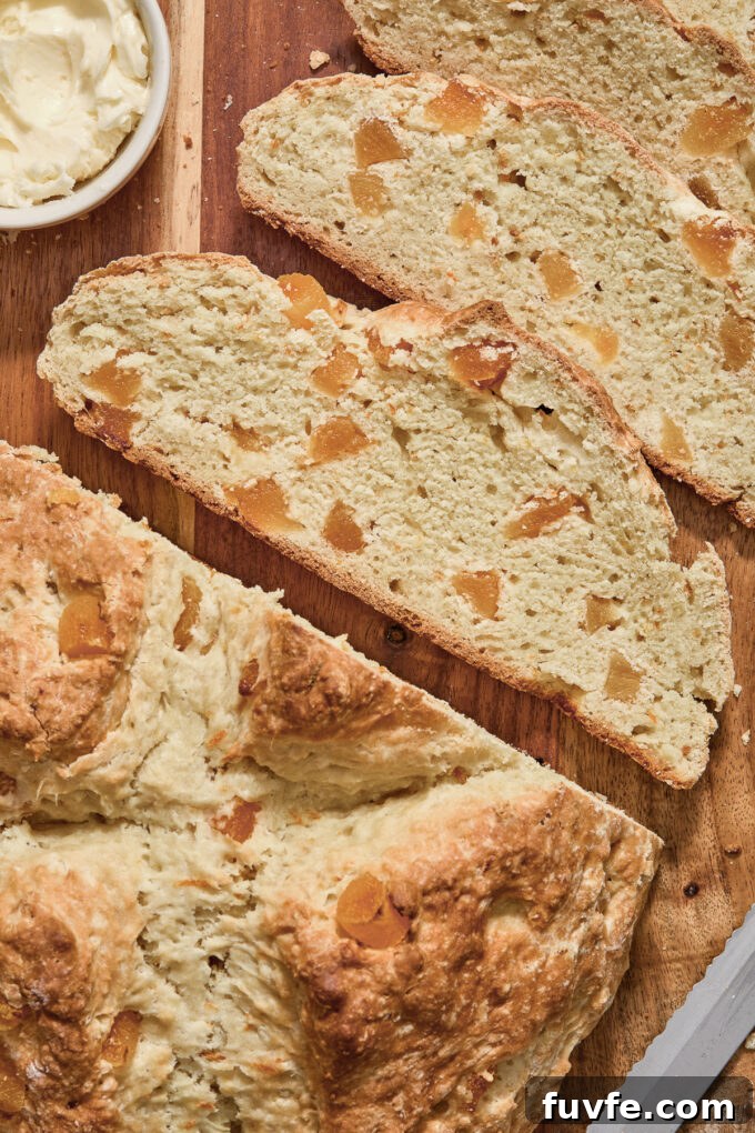 Irish soda bread with apricots and orange sliced on a cutting board.
