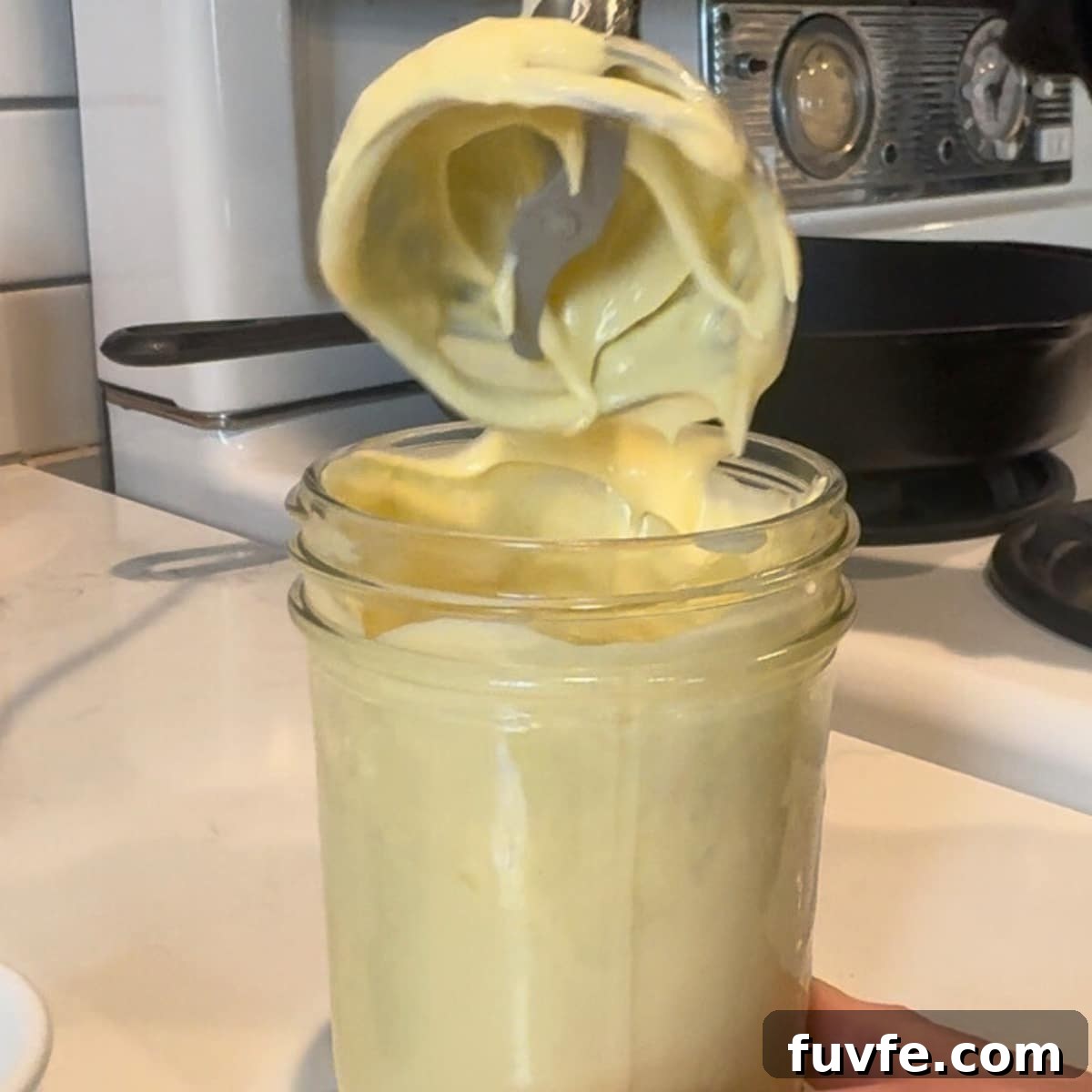 homemade mayo in a mason jar with the emersion blender coming up