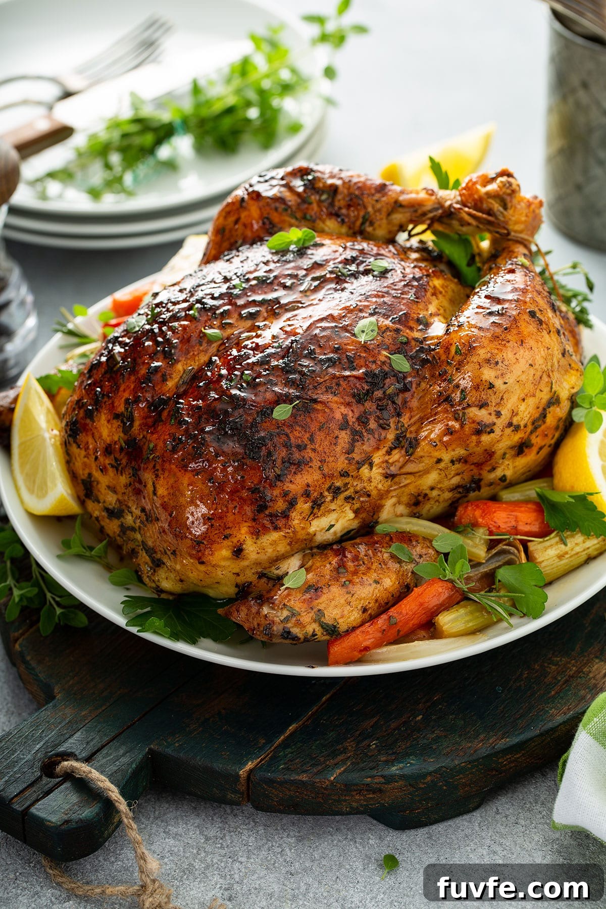 Herb-Butter Roast Chicken Recipe for Juicy Crispy Skin 2 a whole roasted chicken on a white plate with roasted vegetables